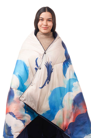 Woman wearing a sleeping bag blanket with a colourful cloud pattern