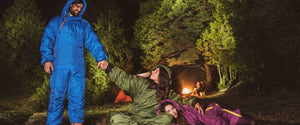 Three adults wearing their Selk’bag Original 6G sleeping bag suits, camping outside at night